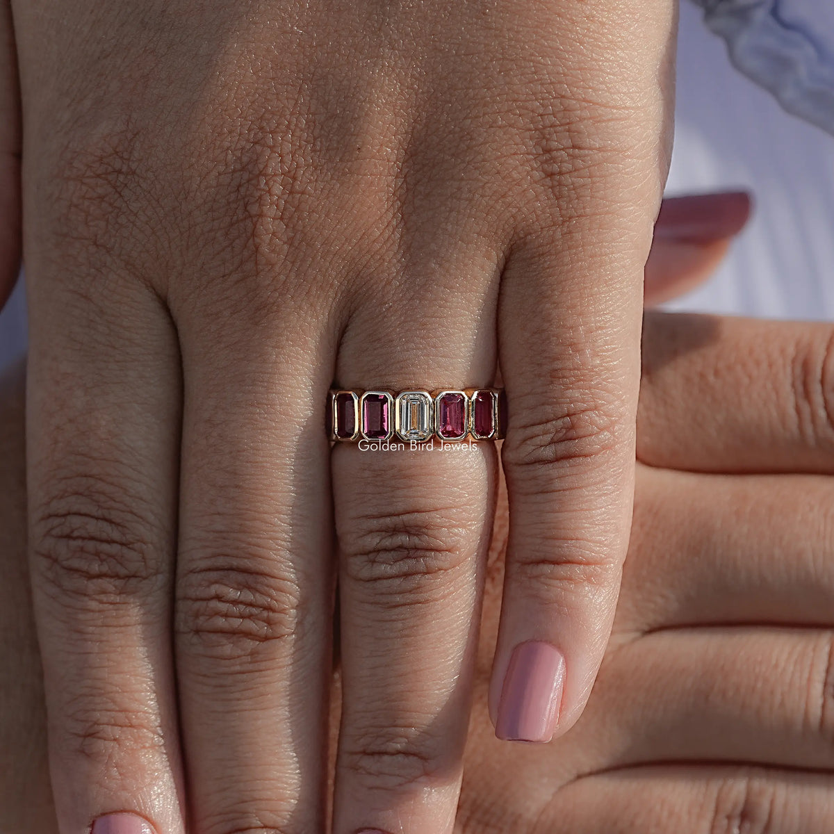 Bezel-set gemstone eternity ring with rectangular stones on hand, front view