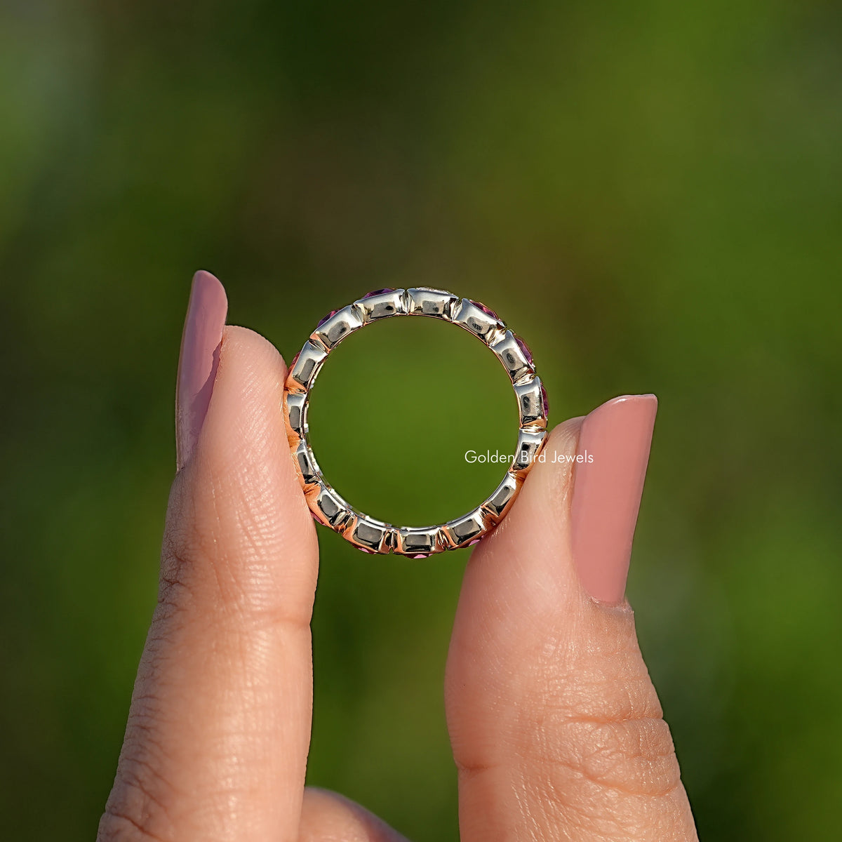 Bezel-set gemstone eternity band with round stones in a metal ring