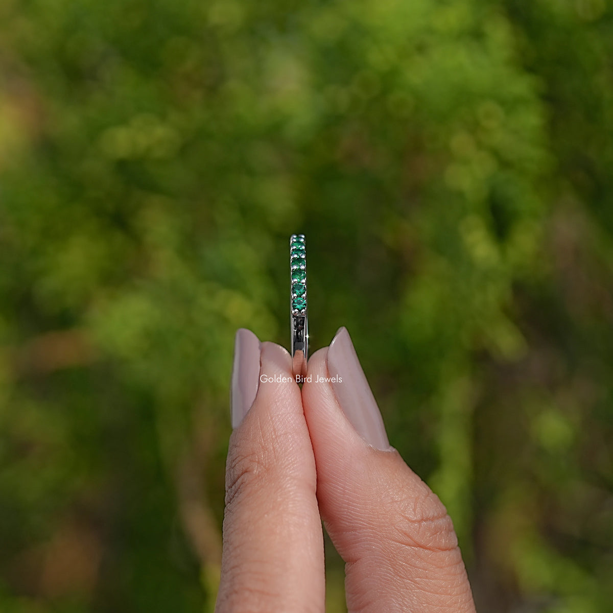 Emerald green eternity band ring with small round stones along the side