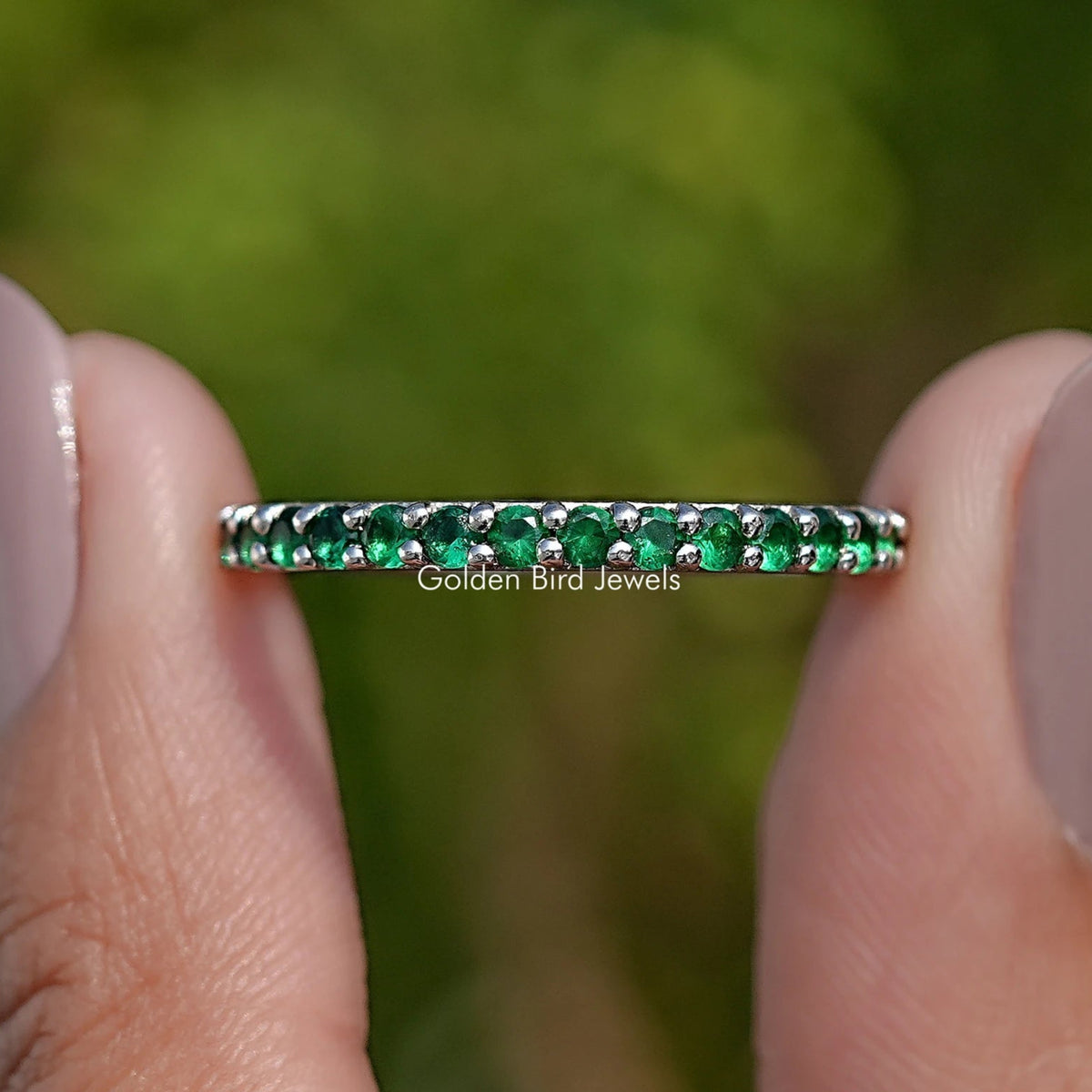 Emerald green round gemstone eternity band with a slim row of green stones