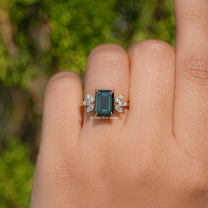 Gold engagement ring with emerald-cut dark green center and four small marquise diamonds