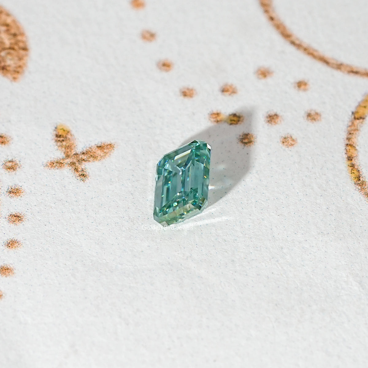 Emerald-cut teal-green moissanite loose stone shown from a slight angle