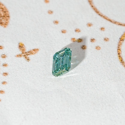 Emerald-cut teal-green moissanite loose stone shown from a slight angle
