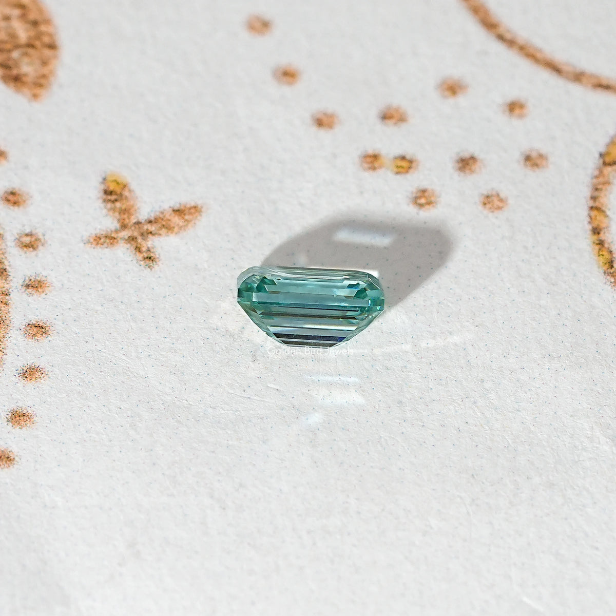 Emerald-cut green moissanite loose stone with faceted corners and long step facets
