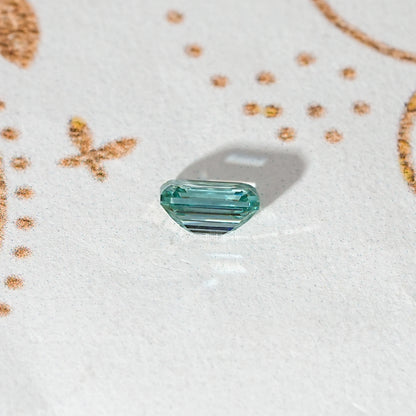 Emerald-cut green moissanite loose stone with faceted corners and long step facets