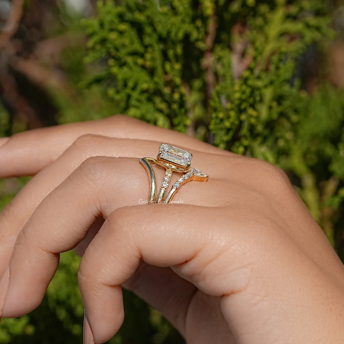 Three-stone bridal ring angled on hand, rectangular center stone and side stones