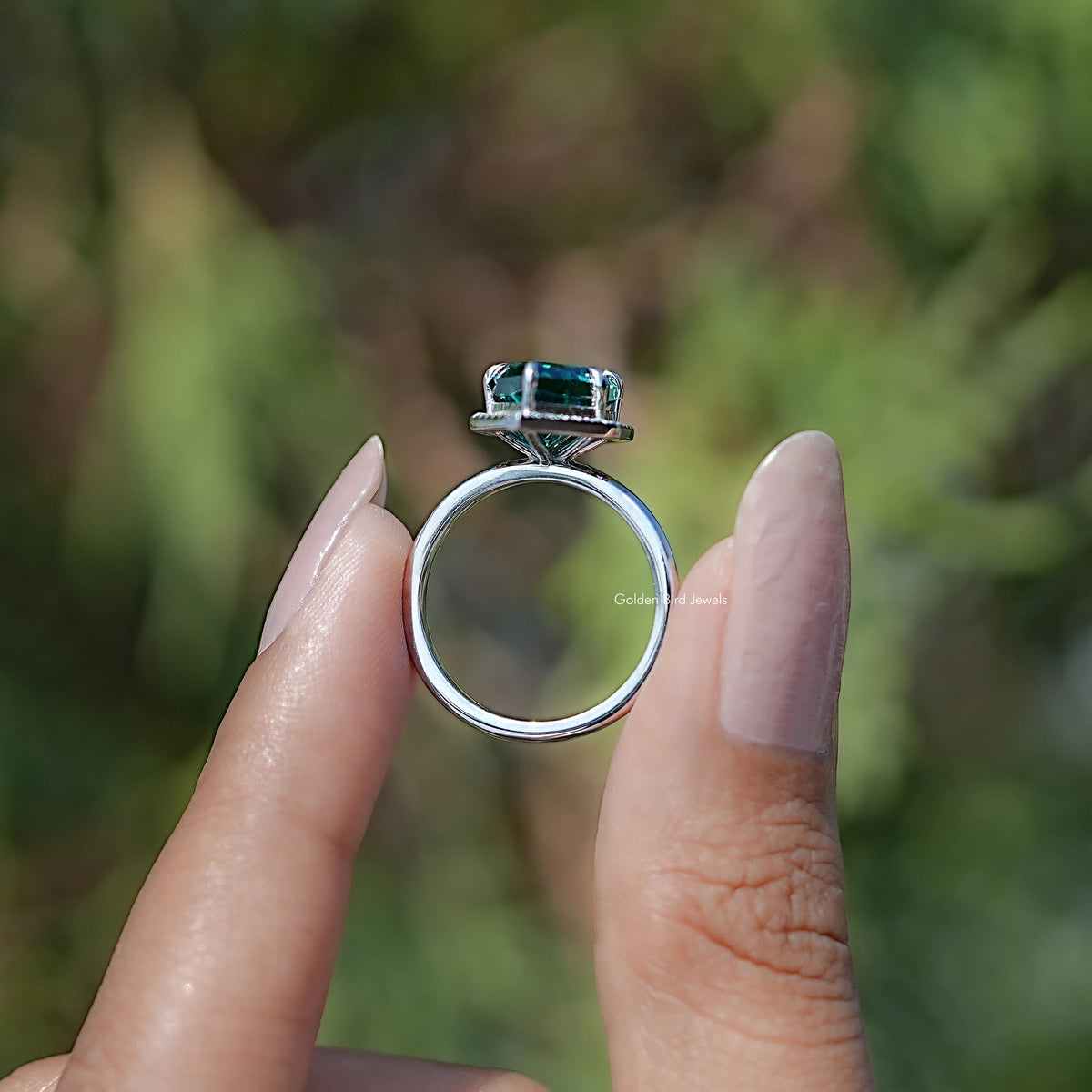 Teal marquise halo engagement ring with rectangular center stone, top view on finger