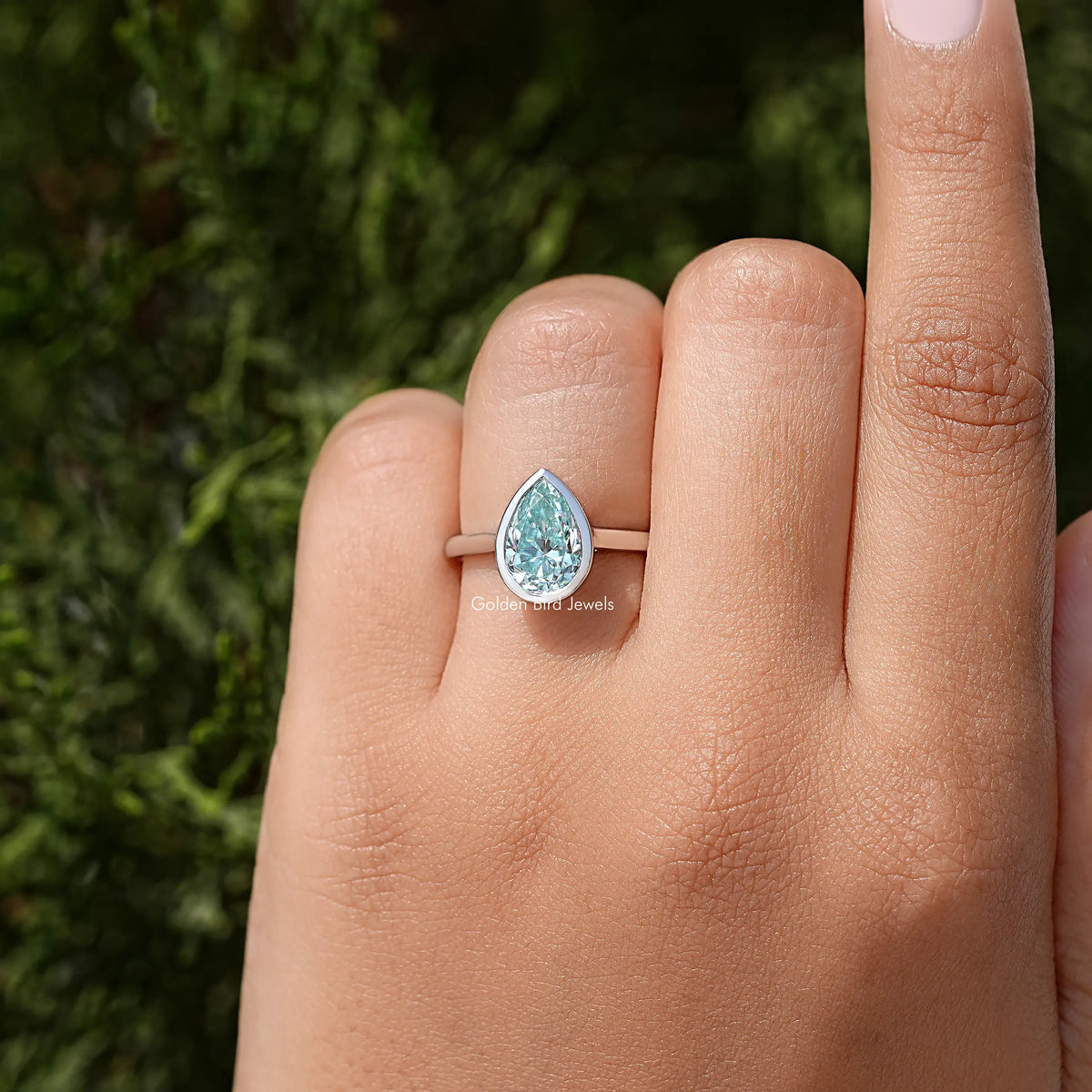 Sterling silver bezel-set pear-cut moissanite solitaire ring on hand