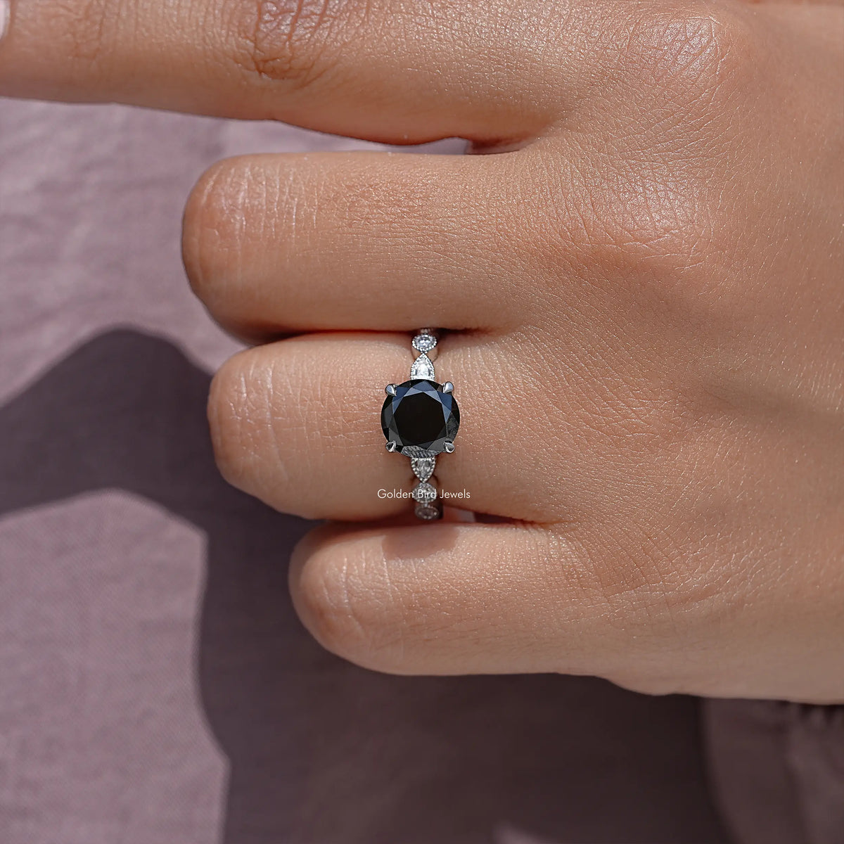 Close-up of sterling silver round-cut moissanite engagement ring with dark center stone