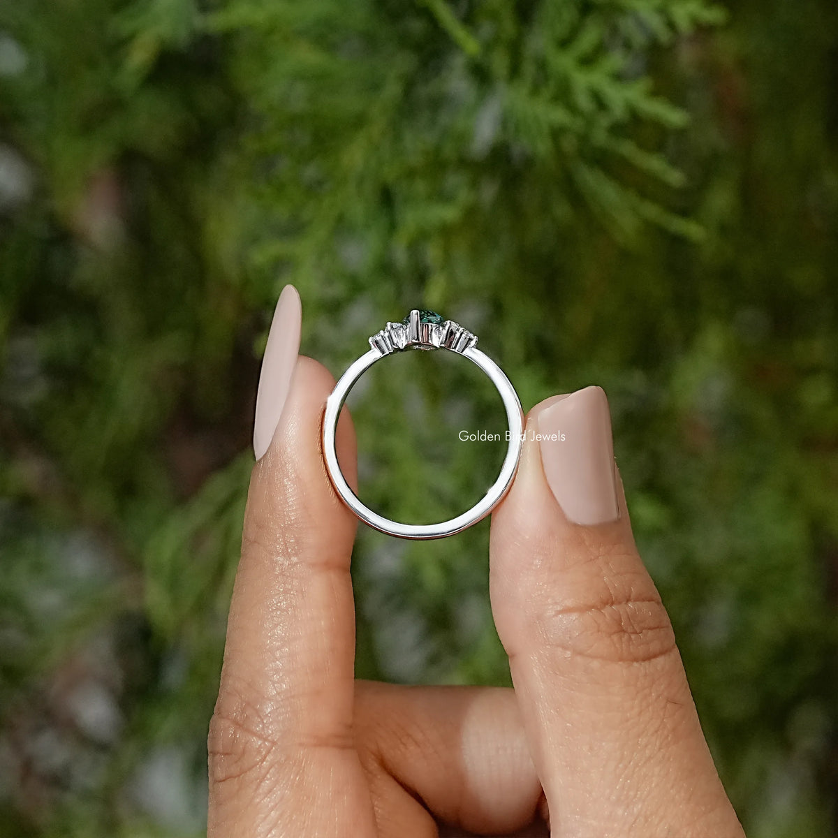 Three-stone engagement ring front view, green marquise center stone with side prong-set stones
