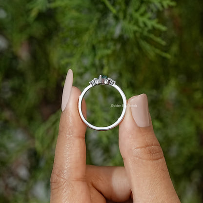 Three-stone engagement ring front view, green marquise center stone with side prong-set stones