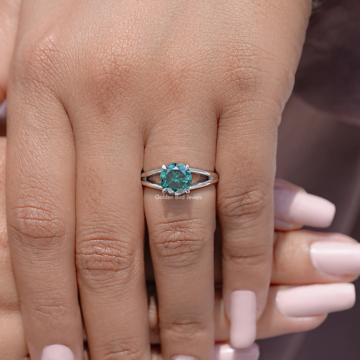 Sterling silver split-shank engagement ring with round teal moissanite center on finger