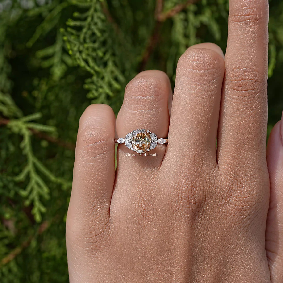 Oval moissanite wedding ring with leaf side stones on hand, close side angle