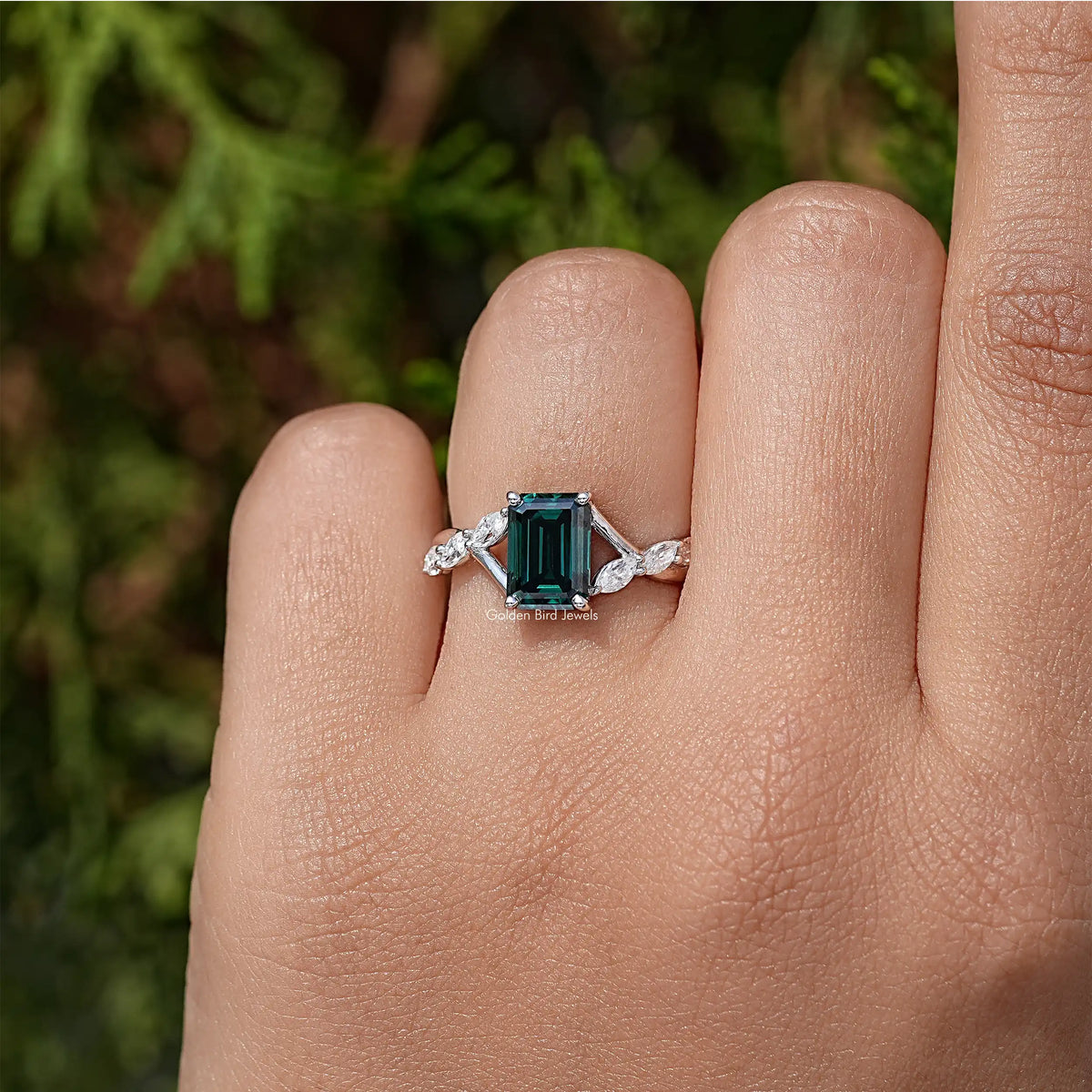 Sterling silver green emerald-cut moissanite ring with small floral side stones.