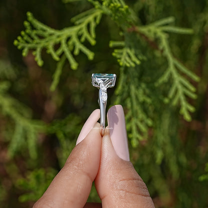 Sterling silver ring with raised teal emerald-cut center and tapered prongs