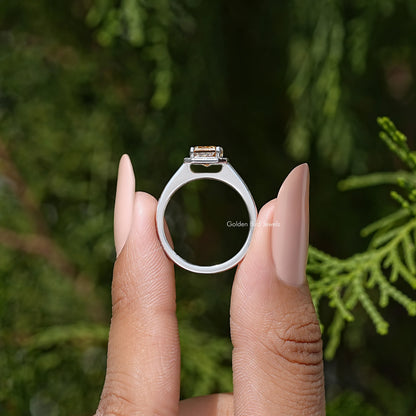 Sterling silver ring with halo around emerald-cut center stone, worn on hands