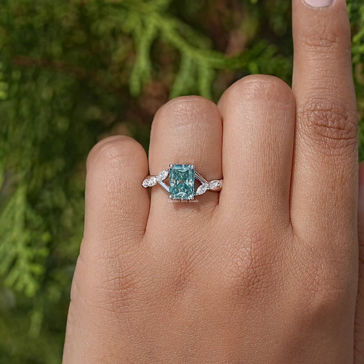 Sterling silver floral anniversary ring with teal emerald-cut center and side stones