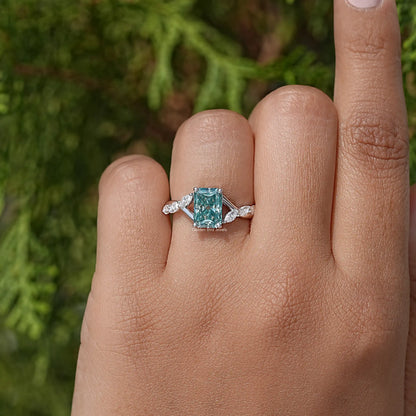 Sterling silver floral anniversary ring with teal emerald-cut center and side stones