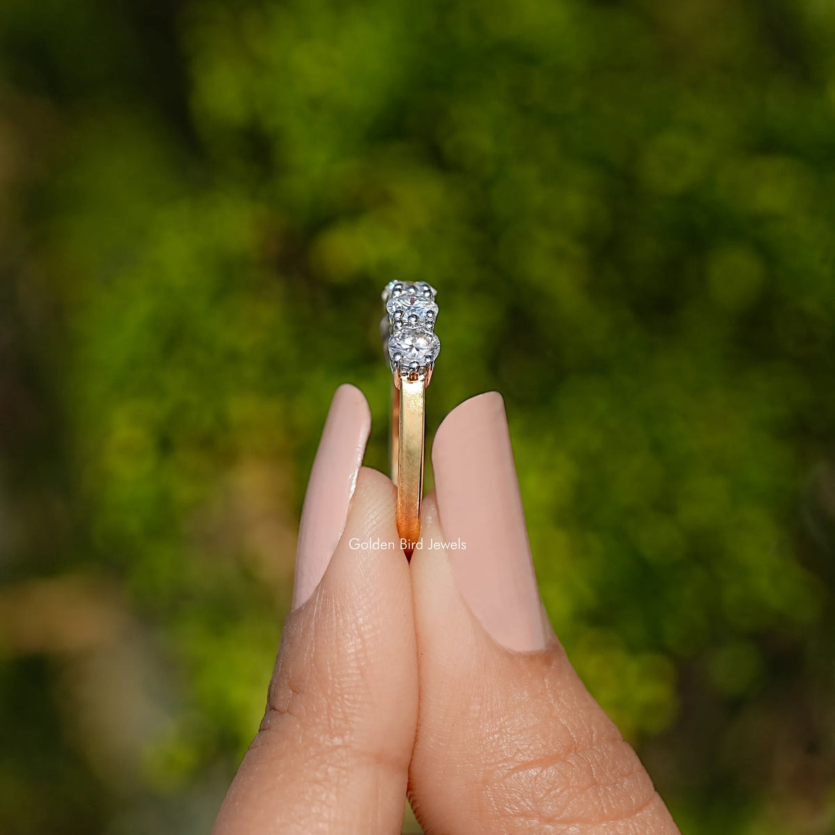 Five-stone round moissanite band in 925 sterling silver, held on fingers