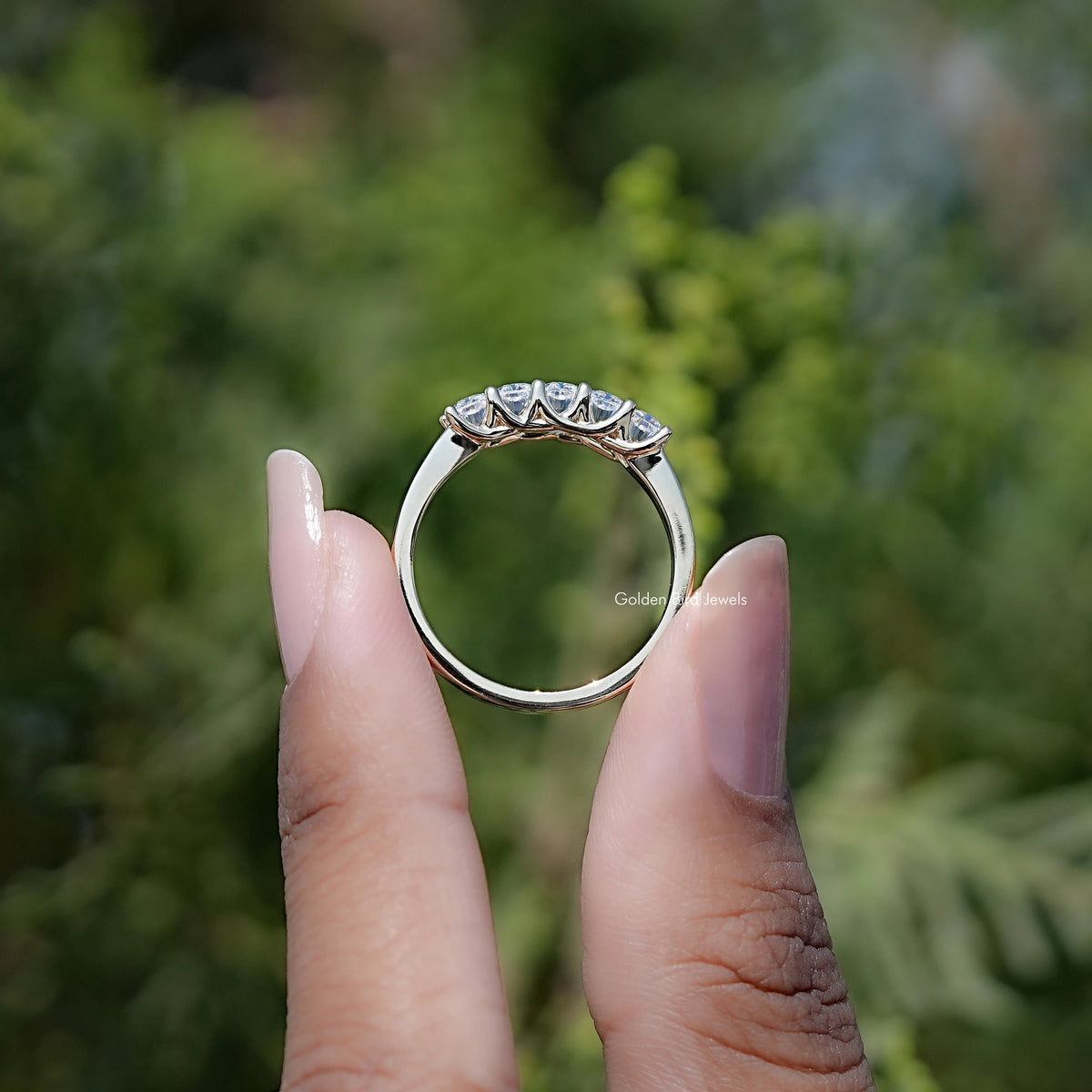 Moissanite radiant-cut ring held upright, halo-like five-stone top band detail