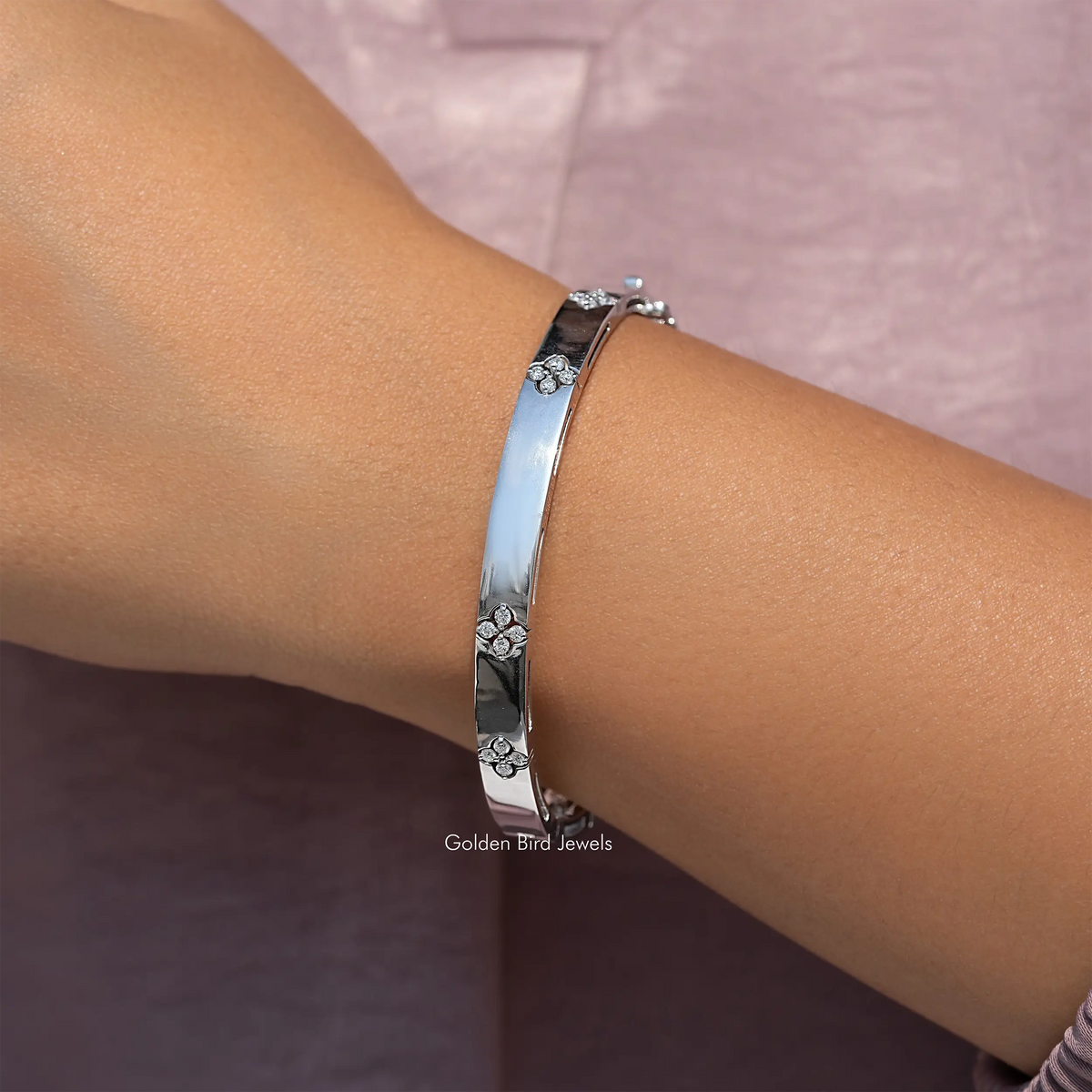 Silver bangle bracelet with floral round diamonds along a polished band