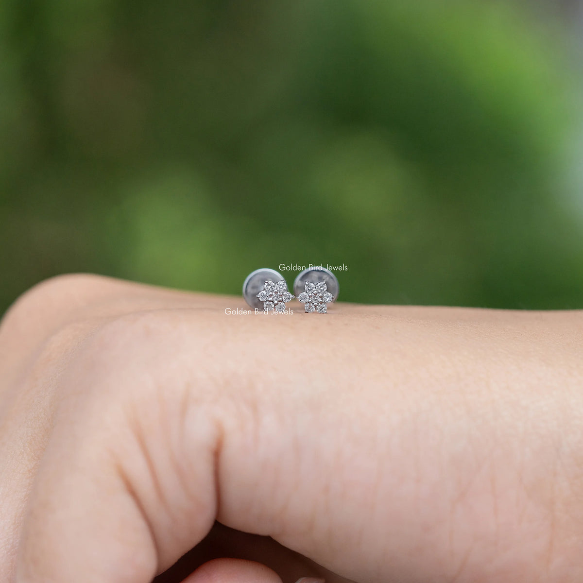 Floral-shaped diamond stud earrings, round stone cluster in silver-tone setting.