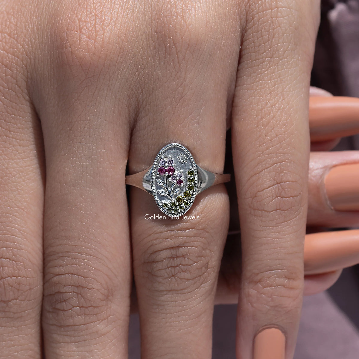 Silver-tone oval signet ring with floral gemstone cluster, pink center and side stones