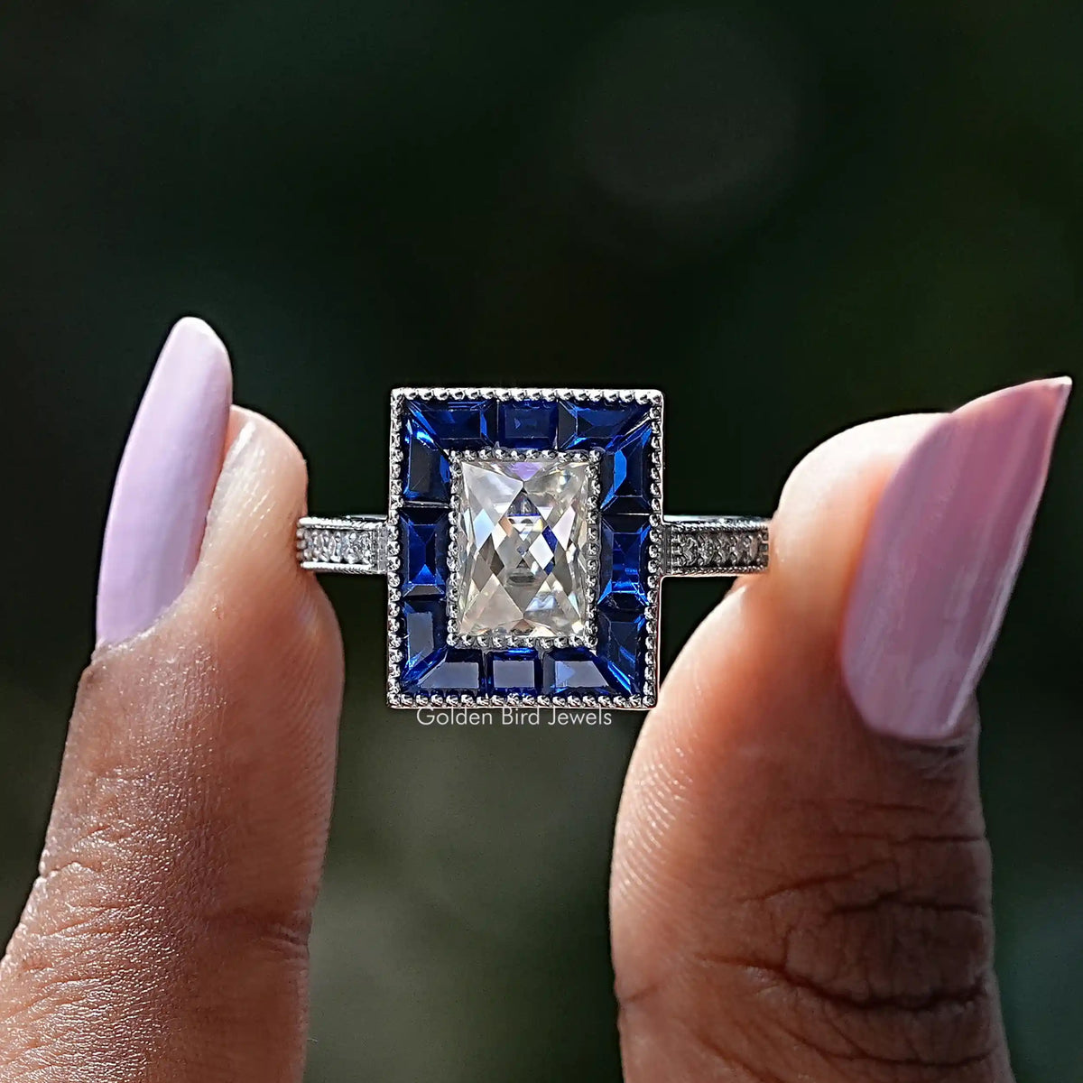 Two fingers holding the Radiant Cut Moissanite Halo Ring