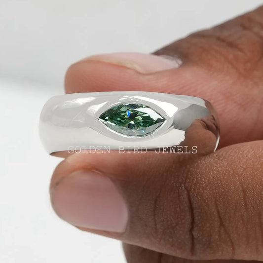 Extreme close-up of silver flush-set solitaire ring with green marquise-cut stone.
