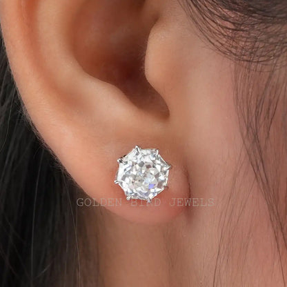 Octagon-cut moissanite stud earrings in white gold on the earlobe