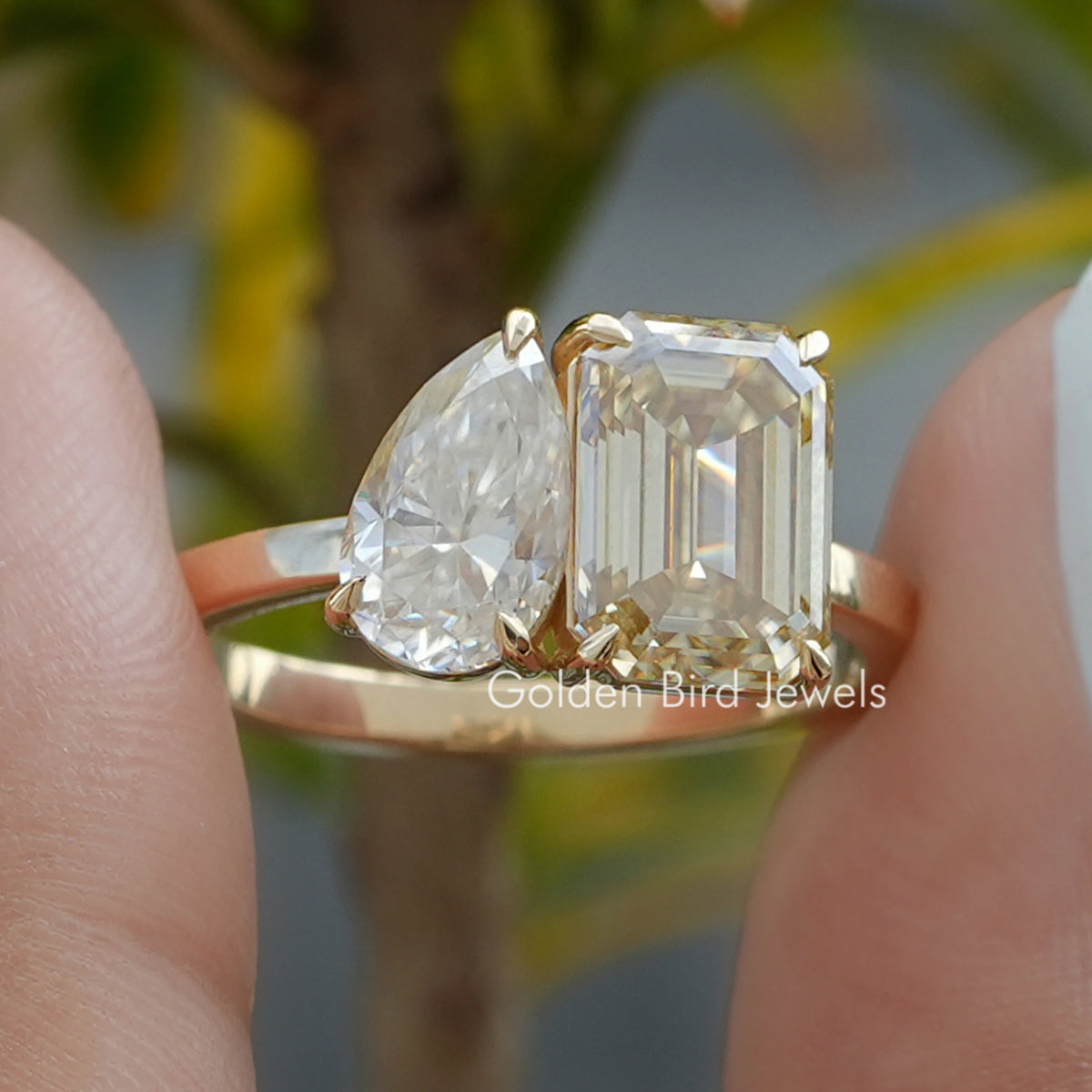 Close-up of two-stone toi et moi ring with pear-shaped and emerald-cut prong-set stones