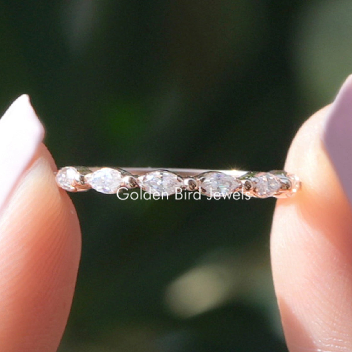 Dainty silver half-eternity wedding band with marquise-cut stones on top half.