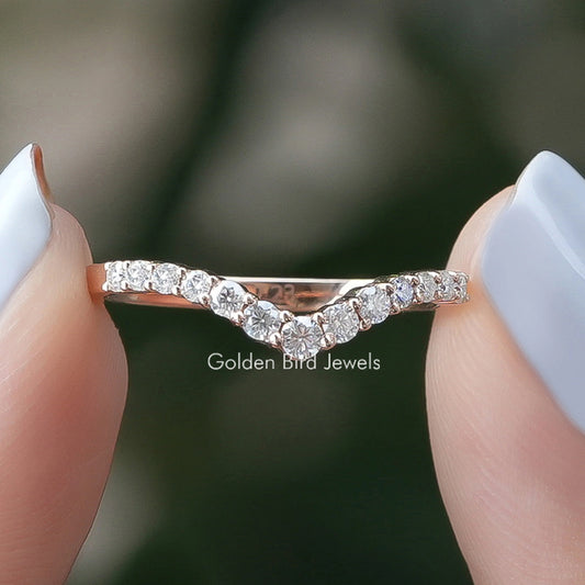 Chevron eternity band ring with round lab diamonds, held between fingers