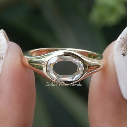 Oval bezel-set solitaire ring with rose-gold tone band and clear oval center stone