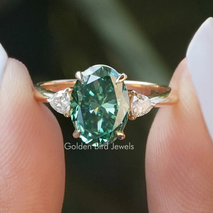 Oval three-stone engagement ring with teal center stone and side round accents, prong set