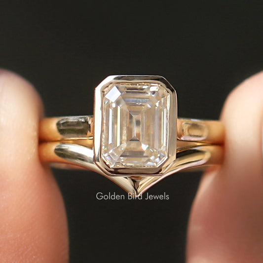 Gold-tone bezel-set emerald-cut ring with curved band and clear center stone