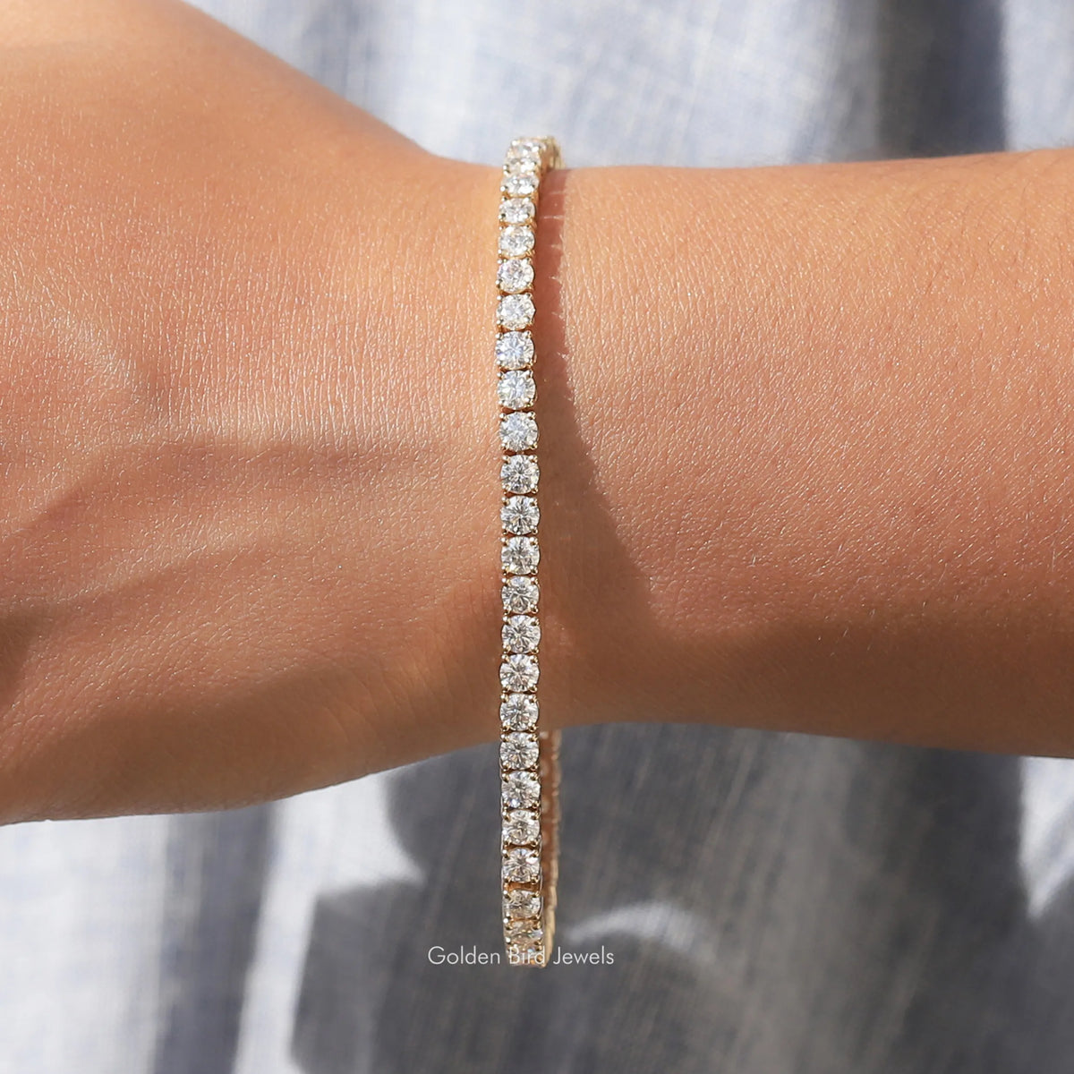 Moissanite tennis bracelet with round-cut stones, gold-tone, centered on wrist
