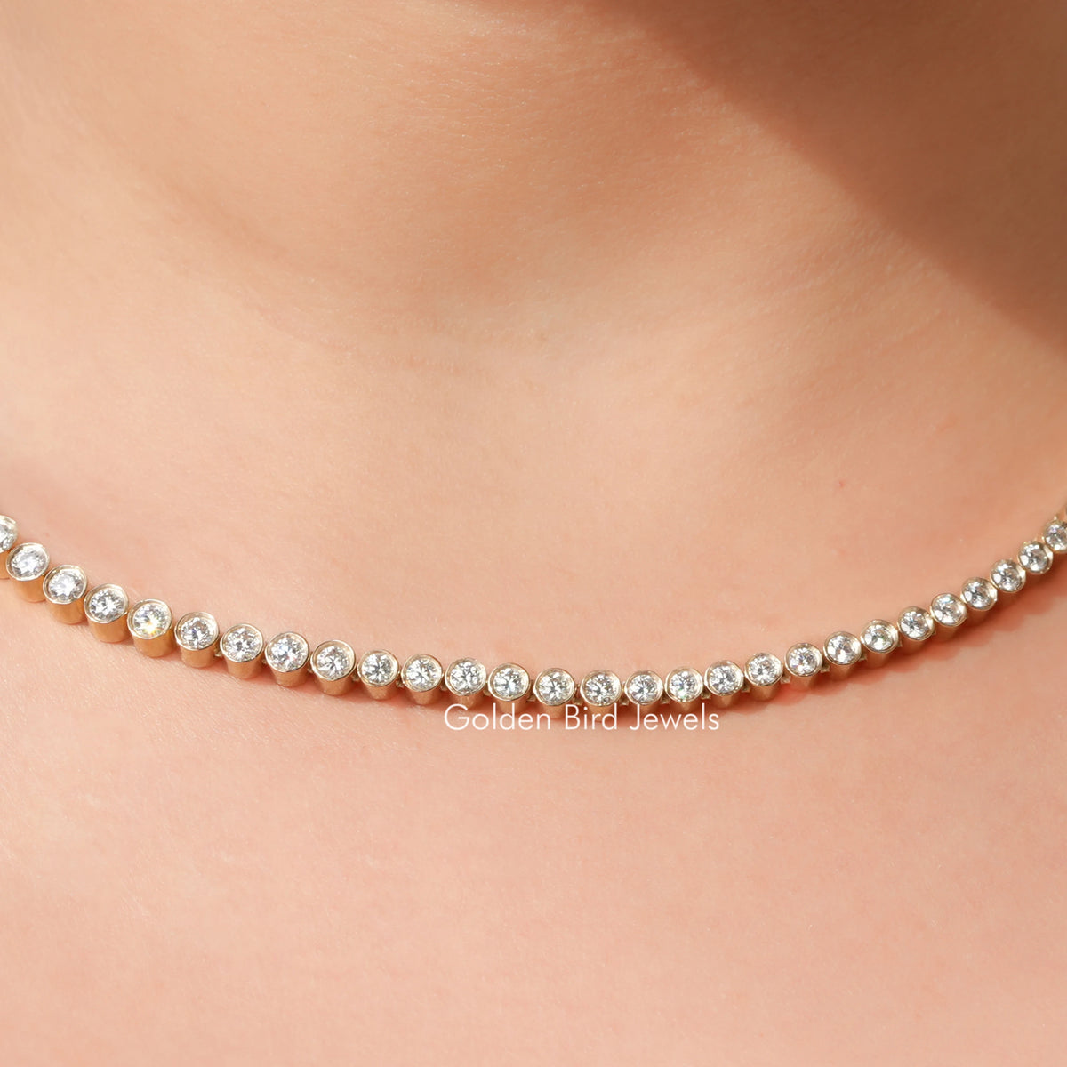 Gold-tone tennis necklace with small round clear stones in a linked row