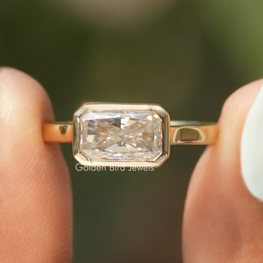 Gold-tone solitaire engagement ring with large rectangular emerald-cut moissanite