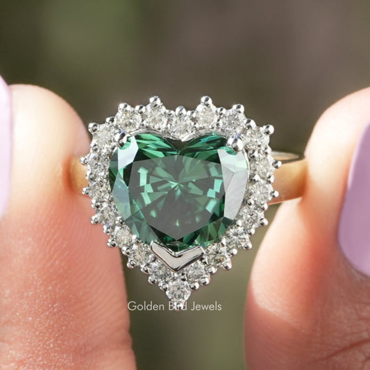 Heart-shaped halo engagement ring with green emerald-cut center stone and clear stones