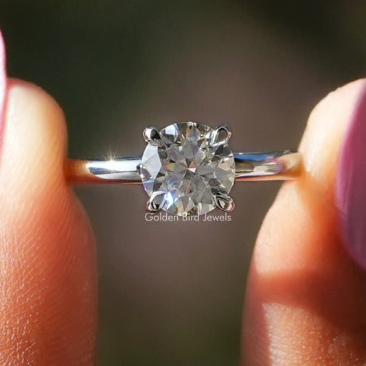 Round solitaire moissanite engagement ring with four-prong setting, polished silver band