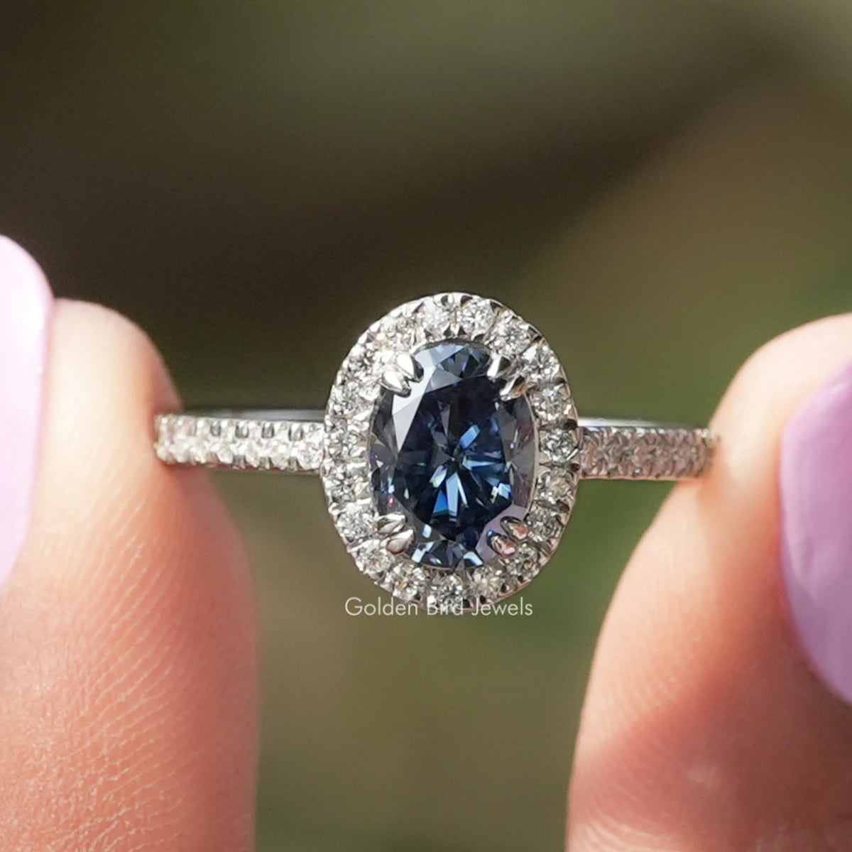 Oval blue sapphire halo engagement ring with round white stones on slim band