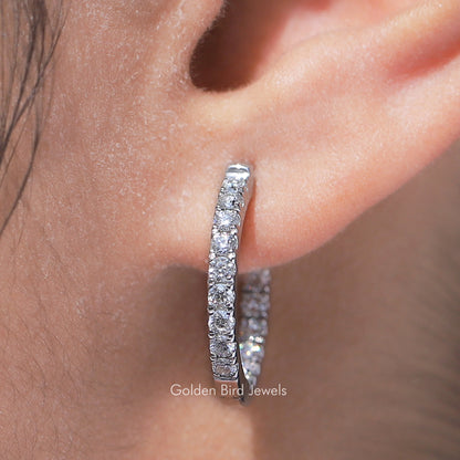 Extreme close-up of round-cut moissanite huggie hoop earring, stone-set band