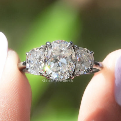 Three-stone moissanite ring with oval center and half-moon side stones in prong setting
