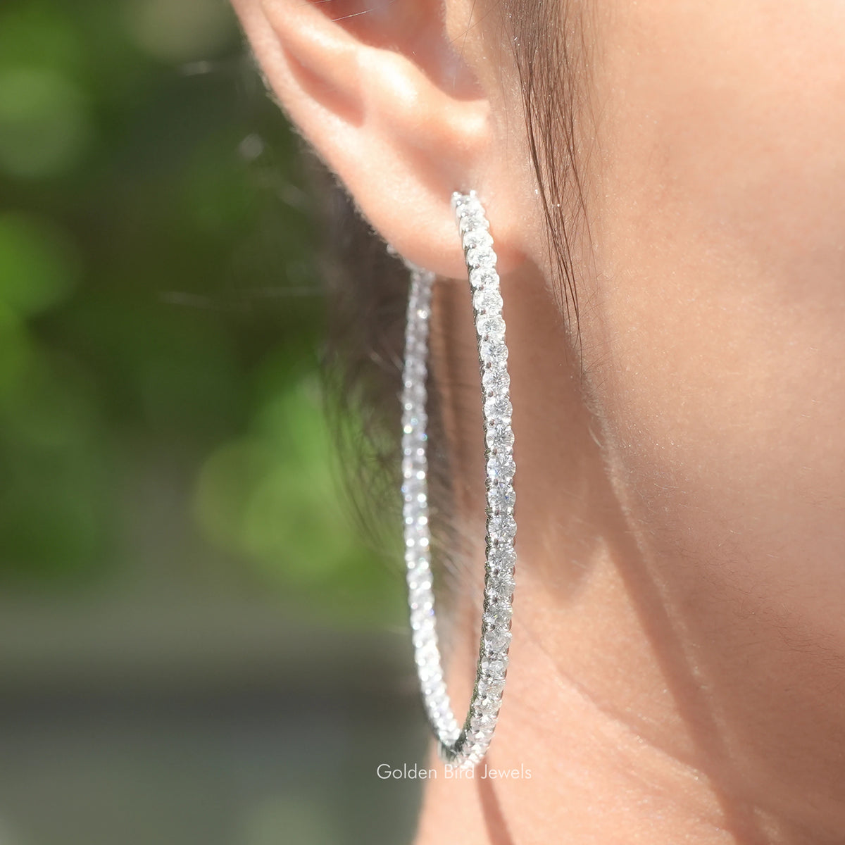 Round moissanite inside-out hoop earrings on ear, silver-tone pavé setting