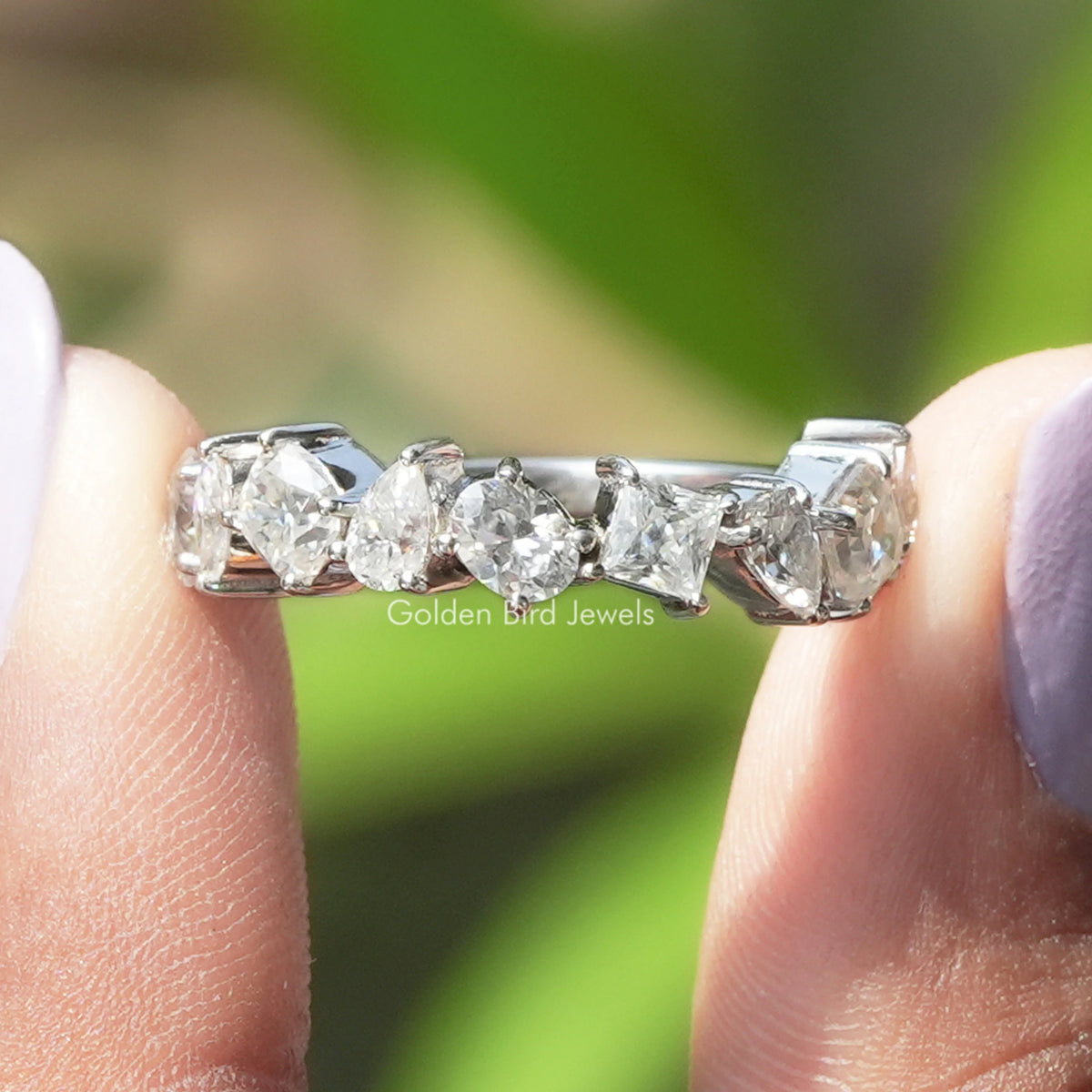 Close-up of white metal moissanite eternity band with large faceted center stones