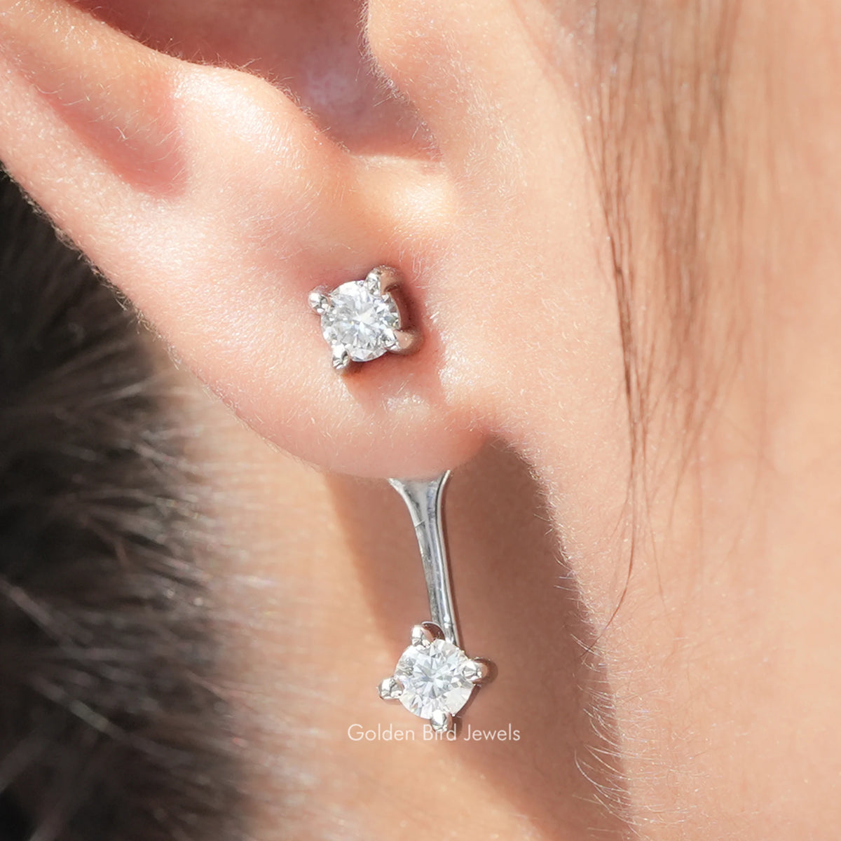 Close-up of silver-tone round moissanite stud and drop earring with screw-back post
