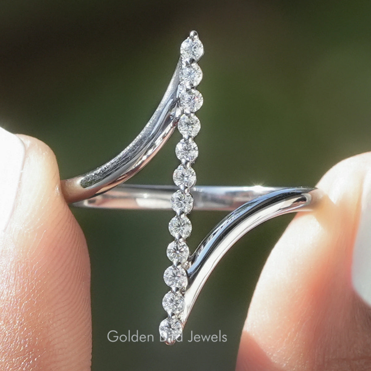 Silver bypass ring with vertical row of round moissanite stones and curved bands