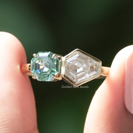 Toi et moi ring close-up: green emerald-cut stone with clear emerald-cut side stone