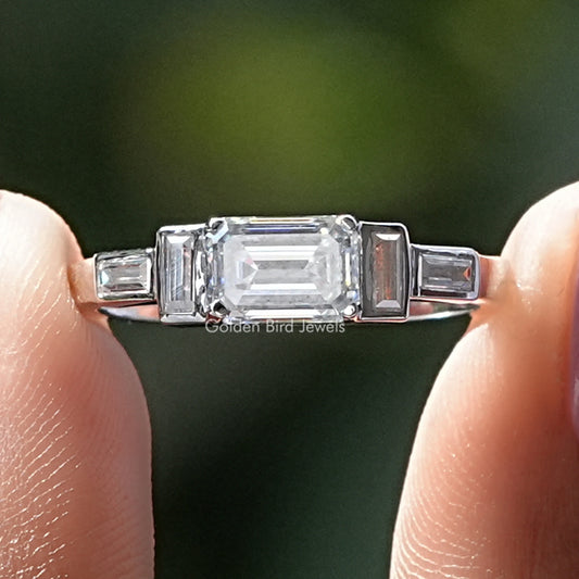 Silver emerald-cut center moissanite ring with baguette side stones, four-prong setting